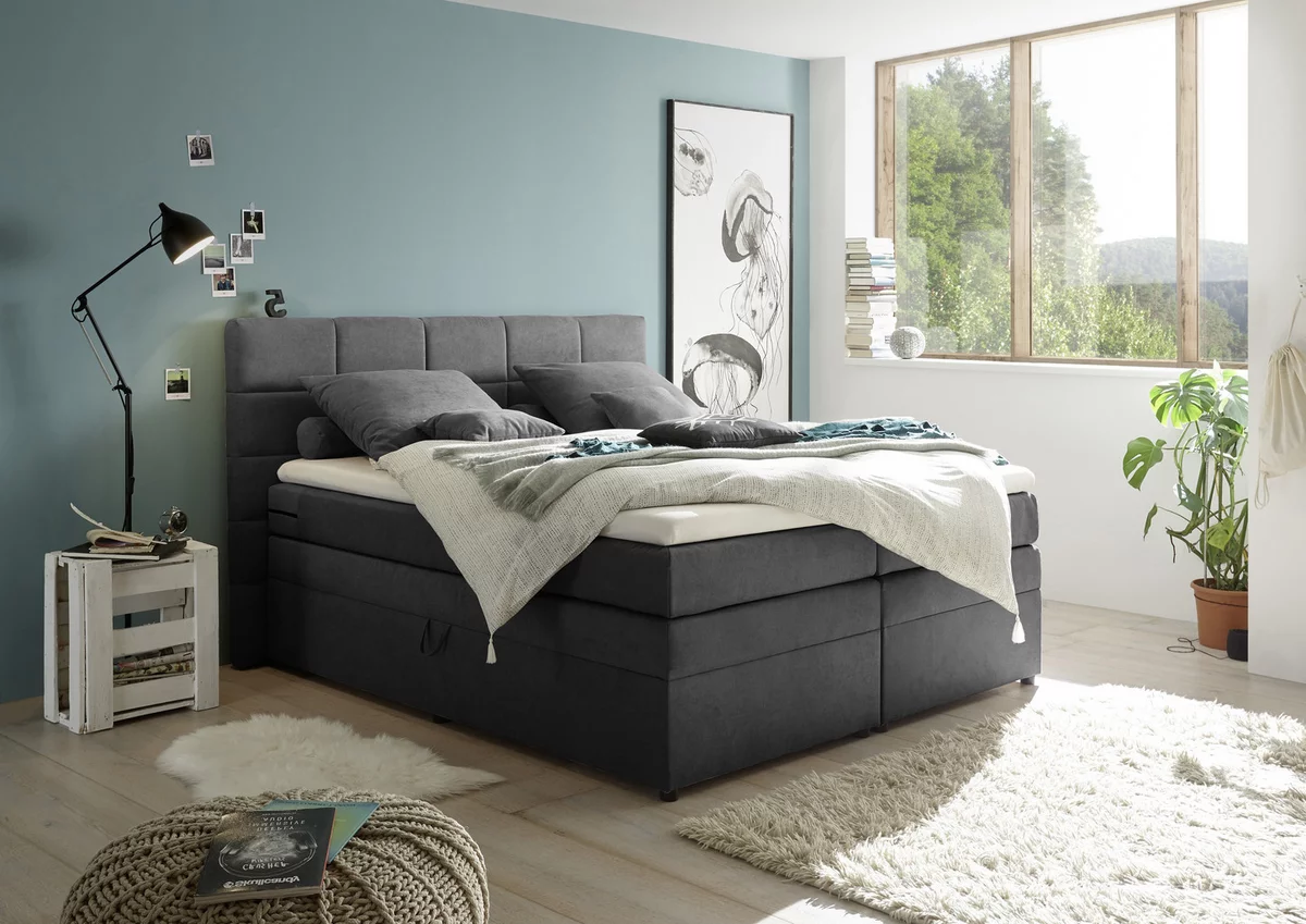 Schlammfarbenes/Graues Boxspringbett  in Samt mit Stauraum und gepolstertem Kopfteil mit Rillenmuster in einem modernen Schlafzimmer von MID.YOU by XXXLutz